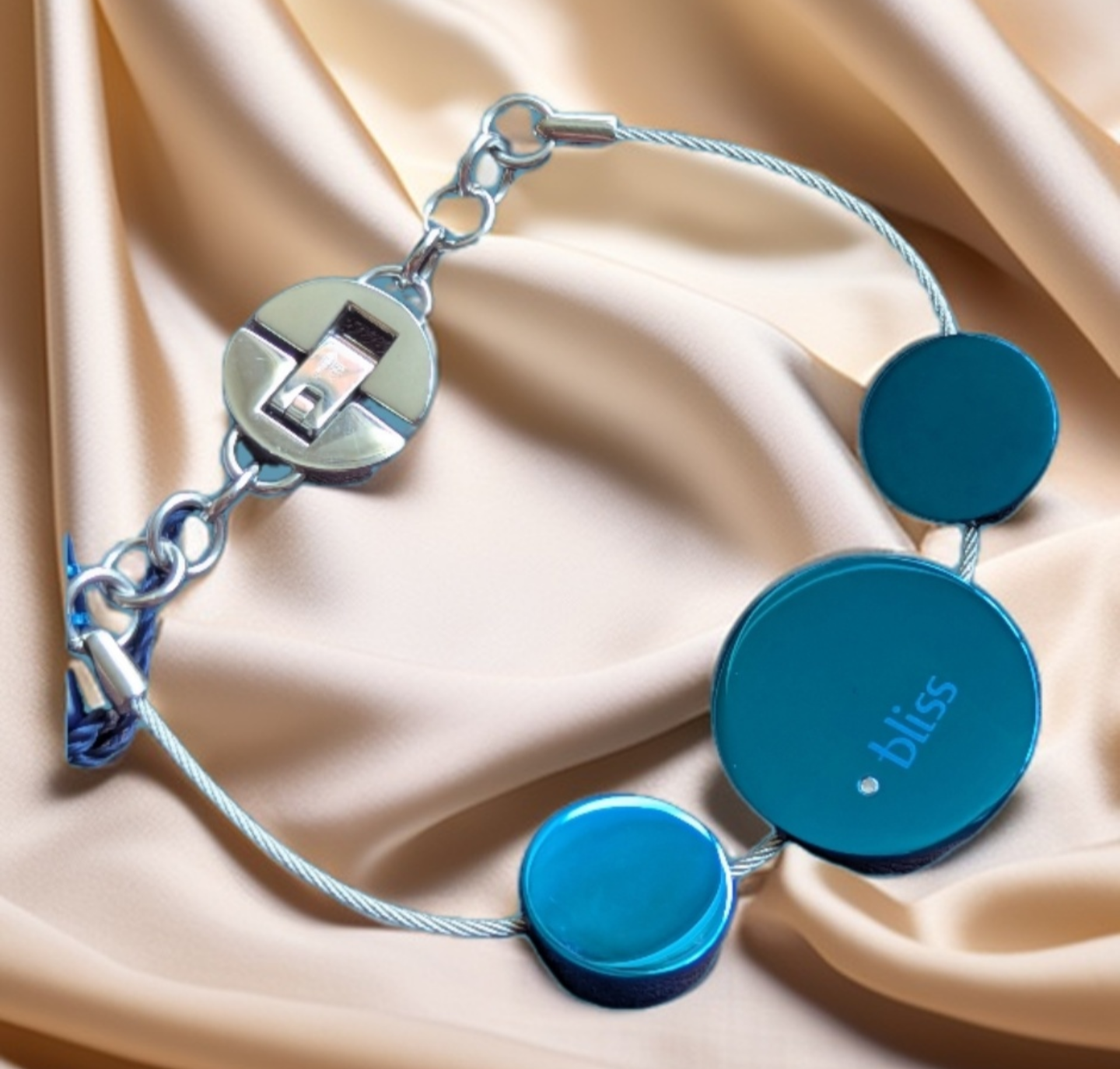 Bliss Damen Armband Edelstahl Kreise blau an Drahtseil Komplettansicht von vorne auf beigen Stoffuntergrund